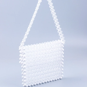 Detail view of white hand-woven acrylic bead bag with transparent拼接 detail on blue background