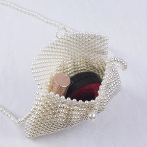 Handmade pearl beaded dumpling bag with crossbody chain shown on marble surface