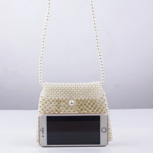 Mini pearl beaded crossbody bag size comparison with smartphone on neutral background