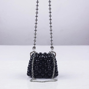 Detailed view of mini black beaded handbag with silver metallic chain and glossy finish