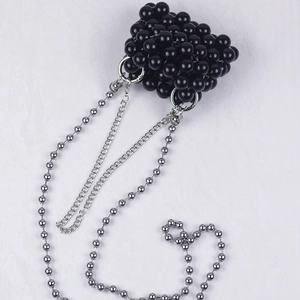 Detail of a black beaded mini chain bag with polished beads and silver metallic link strap