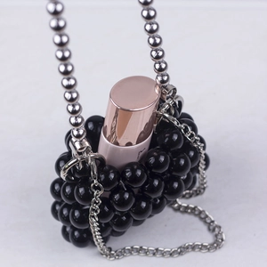 Close-up of black beaded mini bag with silver chain strap and lipstick for scale