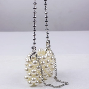 Close-up of handmade mini pearl bag with silver chain straps and woven bead texture
