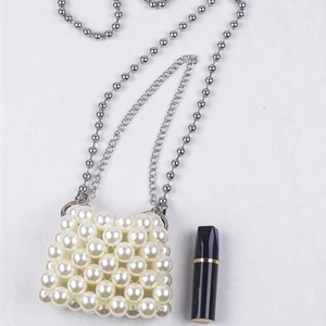 Macro shot of handmade mini pearl bag featuring dual silver chains and white bead texture
