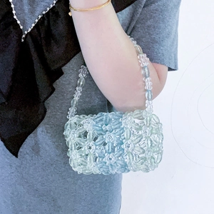 Gros plan d'un mini sac perlé à la main avec perles acryliques bleues et vertes fleuries