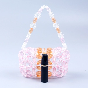 Détail d'un sac à main artisanal en perles avec motif floral et rouge à lèvres de référence