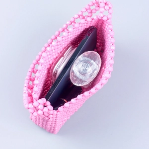 Pink acrylic beaded handmade shoulder bag with phone and perfume inside, top view
