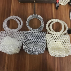 Detailed view of handmade beaded bucket bags in clear, silver and cream woven finishes