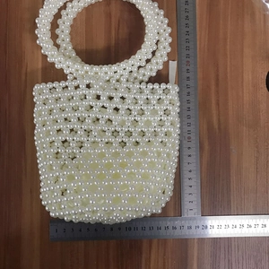 Detail showing dimensions of the handmade white pearl beaded bucket bag on a wooden table