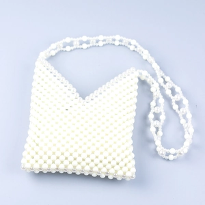 Detail of handmade cream acrylic pearl crossbody bag with V-shaped neckline and woven strap