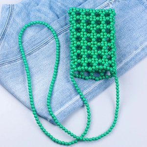 Handmade green beaded woven phone bag with long shoulder strap on denim background