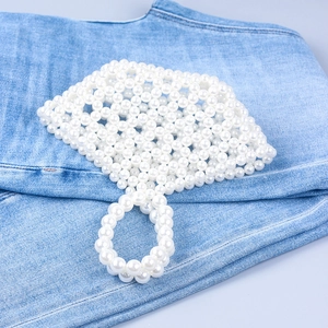 Detail of handmade hollow pearl basket bag showing intricate beaded texture on denim