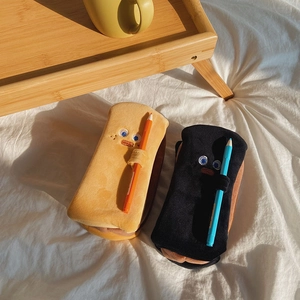 Close-up of toast-shaped plush pencil case with embroidery eyes and side pencil loops