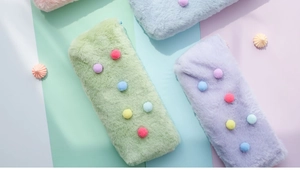 Detail of macaron plush pencil case with colorful pom-pom decor and soft faux fur texture