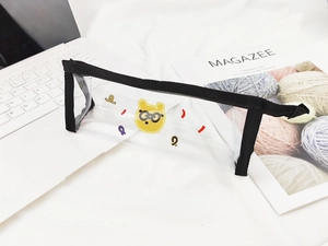 Détail d'une trousse en PVC transparent avec motif d'ours jaune et bordure noire zippée