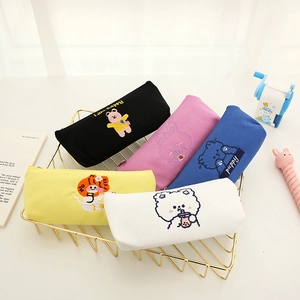 Cute embroidered bear canvas pencil cases in five colors on a desktop organizer