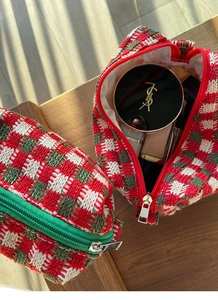 Detail van een grote gebreide ruitjes make-uptas in rood en groen gevuld met cosmetica