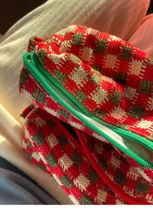 Macro-opname van rood en groen geruite gebreide make-uptas met rits en zachte binnenvoering