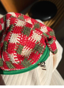 Detailopname van vintage gebreide opbergtas met rood-groen ruitpatroon en metalen rits