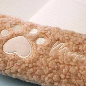 Close-up of plush cat paw pencil case with heart embroidery and Merry text detail