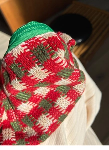 Detailopname van gebreide ruitstructuur in rood en groen met nylon ritssluiting