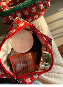 Macro-opname van een grote gebreide ruitjes make-uptas met cosmetica binnenin