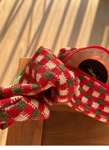 Detail van gebreide rood-groene geruite cosmetische tas met rode ritssluiting erop