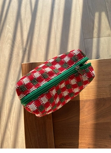 Detailopname van de retro gebreide cosmetische tas met rood-groen ruitpatroon en rits