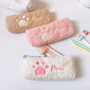 Close-up of soft plush cat paw pencil cases in beige, pink, and cream with Meow embroidery