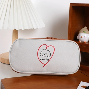 Close-up of canvas pencil case showing dual zippers and cute dog pattern on a desk