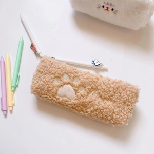 Close-up of fluffy plush pencil case featuring cute cat paw embroidery in light camel brown