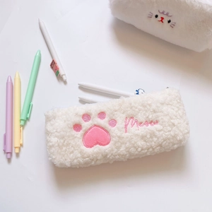 Close-up of pink cat paw embroidery on soft white plush pencil case with Meow text