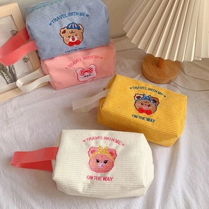 Detail of corduroy makeup bags showing bear embroidery and textured fabric finish