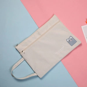 Detail of grey canvas A4 document bag featuring cute cat patch and double zippers