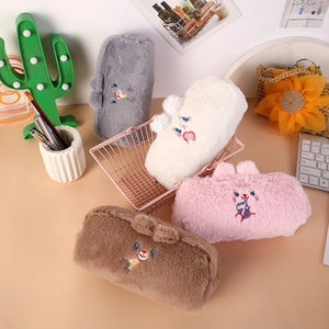 Astucci per matite orsetto di peluche in quattro colori sulla scrivania con cancelleria