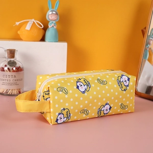 Detail of yellow canvas pencil case featuring cartoon monkey prints and side handle