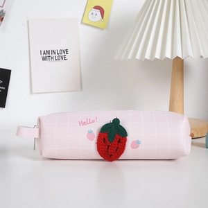 Dettaglio dell'astuccio a scacchi rosa con fragola ricamata e scritta Hello sopra