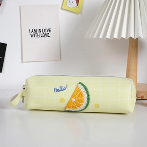 Dettaglio dell'astuccio giallo chiaro con motivo a quadretti e ricamo a limone