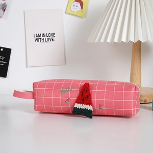 Dettaglio dell'astuccio a quadri rosa con ciondolo a anguria intrecciato 3D e ricamo