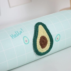 Dettaglio dell'astuccio a scacchi azzurro con toppa avocado all'uncinetto e zip