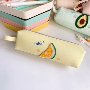 Dettaglio dell'astuccio giallo a quadretti con ricamo arancia e scritta Hello blu