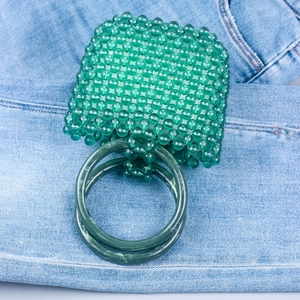 Macro detail of handmade green acrylic beaded handbag with large circular handles