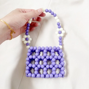 Detail of handmade purple beaded mini handbag with white flower accents on handle