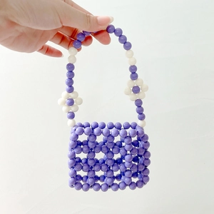 Detail of purple handmade beaded handbag with white floral accents and open grid pattern