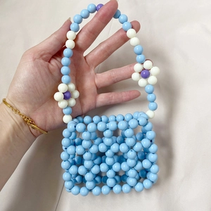 Detail of handmade beaded mini handbag with blue hollow grid and floral patterns