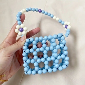 Close-up of handmade beaded mini bag with blue lattice texture and flower details