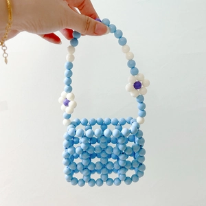 Detail of blue beaded mini handbag with white flower accents and hollow woven grid design