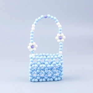 Handmade beaded handbag with macaron grid pattern and white flower charms on blue background