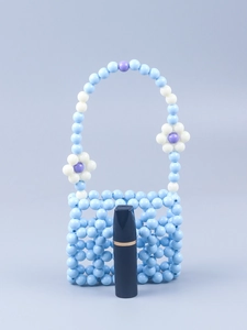 Detail of beaded handbag showing blue hollow square pattern and floral handles
