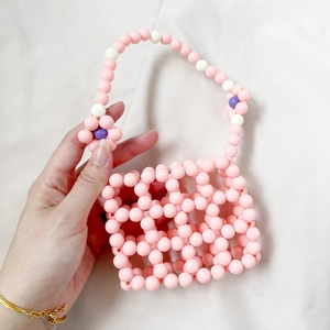 Close-up of pink handmade beaded bag with white and purple floral patterns and grid detail
